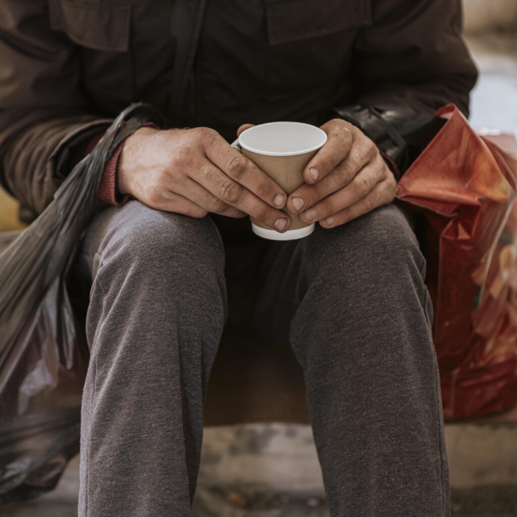 front view homeless man holding cup plastic bag